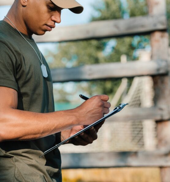 side view of african american tactical instructor making notes in notepad on range