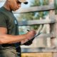 side view of african american tactical instructor making notes in notepad on range