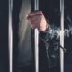 Handcuffed man behind prison bars